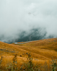 Foggy mountain peaks on Col De La Bonette. Autumn colors. Mountain roads in the French Alps.