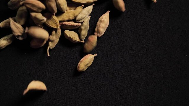 Dry Spices cardamom fall on a black isolated background close-up of slowmo