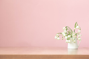 white spring flowers in jug on pink background