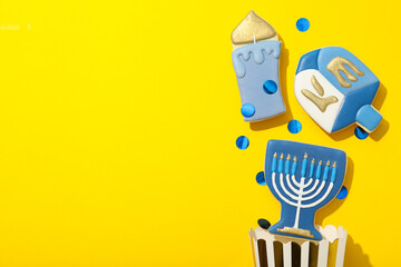 Gingerbread cookies with Jewish signs and popcorn paper bag on yellow background, space for text