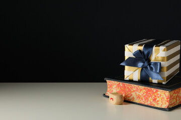 Gift box and book on black background, space for text
