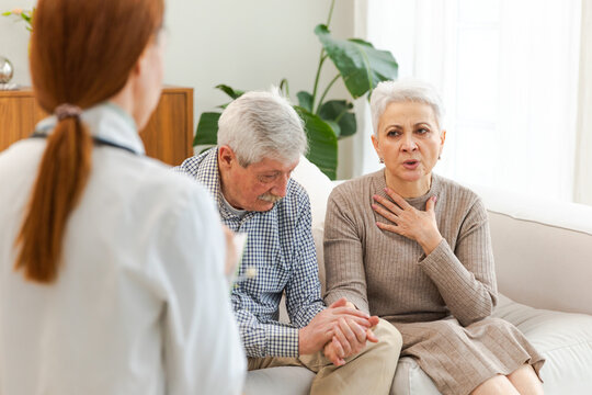 Female doctor examining older senior couple in doctor office or at home. Old woman man patient and doctor have consultation in hospital room. Medicine healthcare medical checkup. Visit to doctor