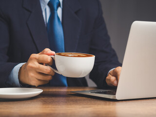 Businessman holding a cup of coffee while working at a desk