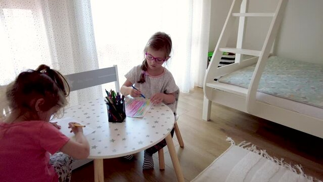 Two little girls, sisters drawing pictures at home. Girls enjoys painting