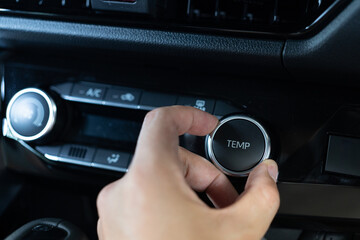 Hand turning knob on modern car cooling temp adjust. Asian male hand on dashboard air conditioner car interior. Set up air conditioner in the car. Cooling air in the car.