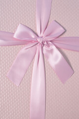 Shiny pink satin ribbon on pink background. Pink bow and pink ribbon. Creative gift concept.