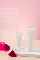 Two empty cosmetic tubes are placed on the podium, next to red dragon fruit extract stored in an...