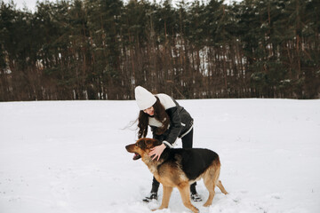 Young woman walk the dog German Shepherd in winter field forest, running playing with snow, training the animal in harsh conditions, wind blowing. Christmas Time, New Year
