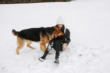 Young woman walk the dog German Shepherd in winter field forest, running playing with snow, training the animal in harsh conditions, wind blowing. Christmas Time, New Year
