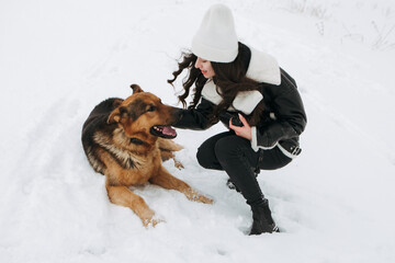 Young woman walk the dog German Shepherd in winter field forest, running playing with snow,...