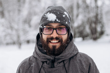Young man covered with snow having fun in winter after playing snowballs, snowy season in city...