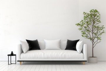 a white couch with black pillows and a plant in front of it