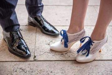 Elegant black patent leather men's shoes and white women's shoes with blue laces and lace