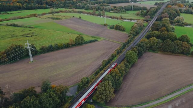 Regional train crossing a countryside area with agricultural fields in Europe Germany , aerial footage	