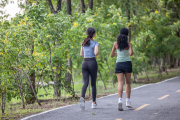 Stylish female runners in modern attire, discover serenity. Reenergize amid jogging the parkway.