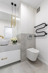 A modern bathroom in light colours with gold fixtures and a bouquet of white flowers
