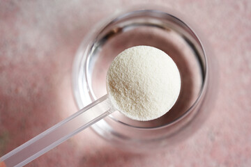 Collagen powder in a plastic scoop with a glass of water - obrazy, fototapety, plakaty
