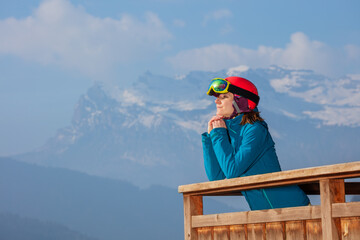 Skier on chalet balcony marvels at Alps view