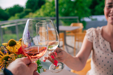 a mand and a wonman make a toast with a glass of rose and a glass of white wine