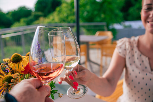 a mand and a wonman make a toast with a glass of rose and a glass of white wine
