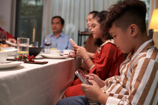 Kids spending time scrolling social media on smartphones at family dinner