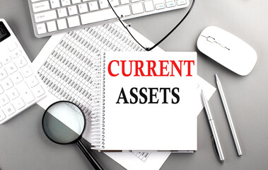 CURRENT ASSETS text on notebook with clipboard and calculator on a chart background