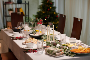 Christmas dinner table with traditional Vietnamese dishes decorated with candles and greenery