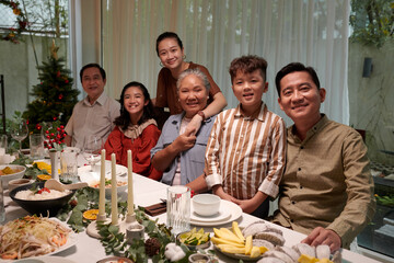 Happy big Vietnamese family sitting at dinner table served for New Year celebration