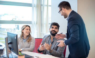 Confident business professionals talking to each other at office table, speaking, gesturing, teaching, explaining work tasks.