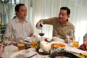 Fototapeta na wymiar Vietnamese men drinking wine and sharing stories at dinner party