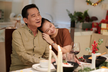 Smiling woman resting head on shoulder of husband at Christmas dinner