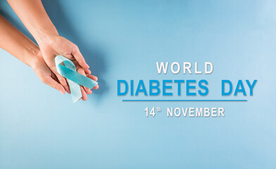 World diabetes day awareness concept. Hand holding blue ribbon, symbolic bow color raising awareness in diabetes day on pastel background,  14 November.