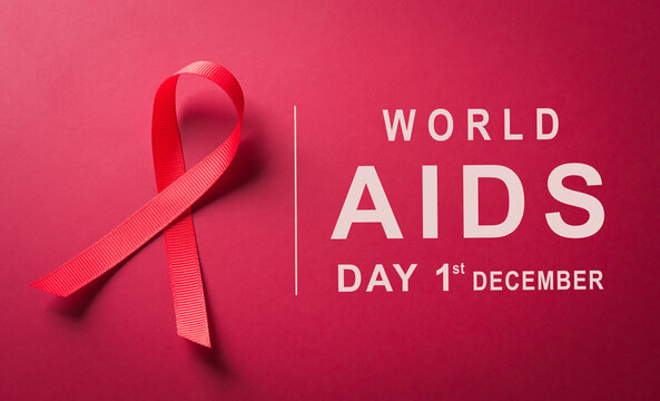 Closeup red ribbon HIV, world AIDS day awareness ribbon on red background. Healthcare and medicine concept.