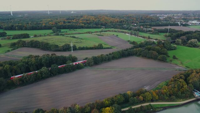 Regional train crossing a countryside area with agricultural fields in Europe Germany , aerial footage	