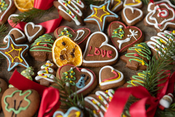 Ręcznie dekorowane ciastka z kolorowym lukrem ułożone na drewnianej desce w świątecznej aranżacji.