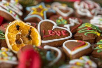 Ręcznie dekorowane ciastka z kolorowym lukrem ułożone na drewnianej desce w świątecznej aranżacji.