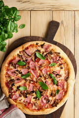 Pizza. Traditional Bacon pizza with ham, mushrooms, pickled cucumber and cheese and cooking ingredients tomatoes basil on wooden table backgrounds. Italian Traditional food. Top view. Mock up.
