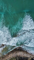 an aerial view of waves coming into the ocean near a coastline