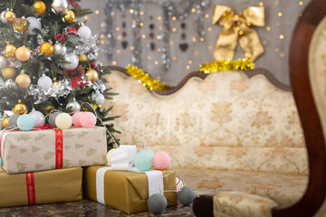 New Year Eve in room with a sofa and different gift boxes on it and big decorated Christmas tree next to it