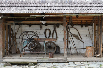 Collection of planers and retro wood saws hang on a wooden wall near an old house. Carpenters plane and other things on the wall