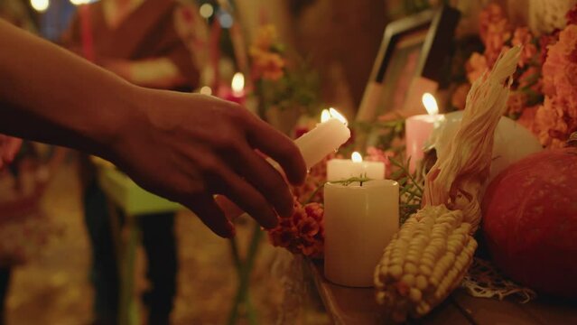 Cropped shot of unrecognizable female hand lighting altar candles in cozy autumn backyard in evening on Day of the Dead
