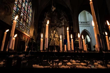 Gordijnen Virgin Mary in church and burning candles near her. © Elena