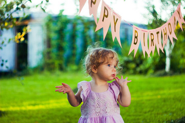 Cute little girl in dress. Birthday celebration outside in the backyard. Big garden party. Birthday party. 