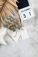 White blank paper tag on craft gifts boxes and Christmas decor on grey conkrete background. Christmas greeting card mockup