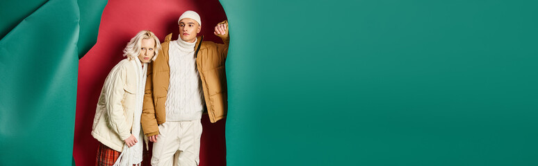 young man in beanie and winter jacket near blonde woman on torn turquoise and red background, banner