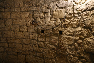 Slavery and bondage strong steel old shackles on stone wall in castle cellar or tomb
