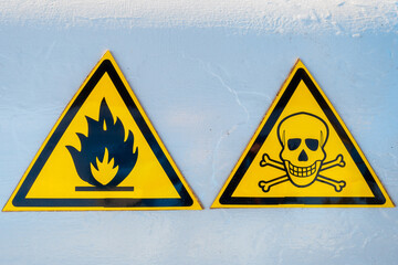 Danger warning signs. Two yellow triangles. Skull and bones. Fire. Caution: Explosive. Be careful...