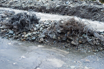 Metal mesh used to strengthen banks and river beds from landslides and mudflows is crushed and destroyed. Consequences of mountain river flood. Background.