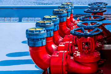 Five red fire hydrants on a fire line on a ship.