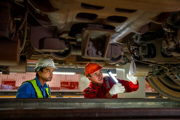 Professional engineer and technician workers check and maintenance under the train with use light tube to support in train factory workplace. - obrazy, fototapety, plakaty